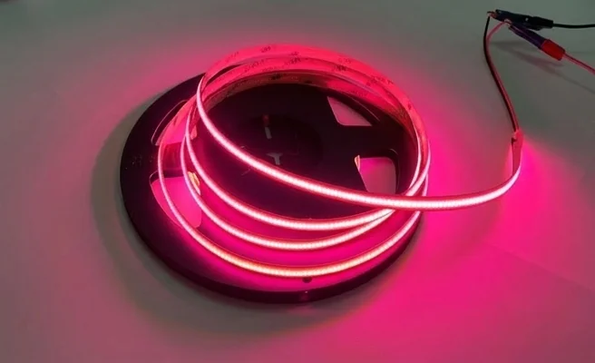 Zbliżenie na taśmę LED COB 480 9W/m RÓŻOWA 12V IP20 /5m/P EC20307 z bardzo gęsto rozmieszczonymi diodami, świecącą jednolitym różowym światłem.